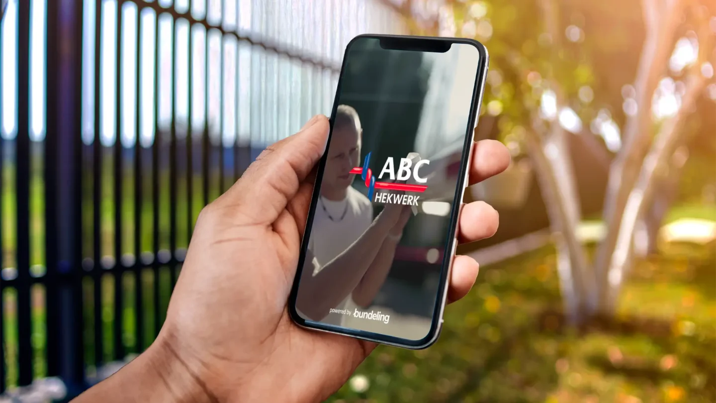 Smartphone met de ABC Hekwerk app naast een hek