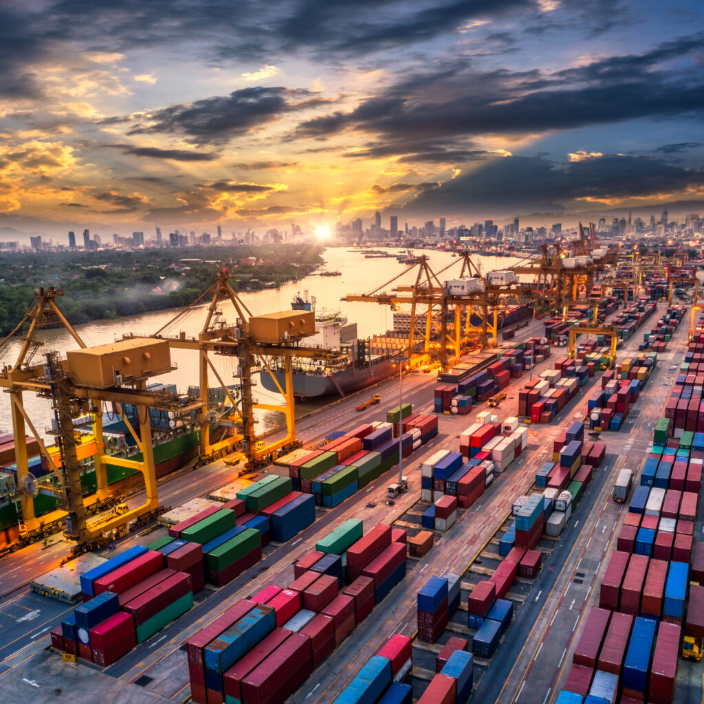 A port filled with containers and cranes with a city as the skyline