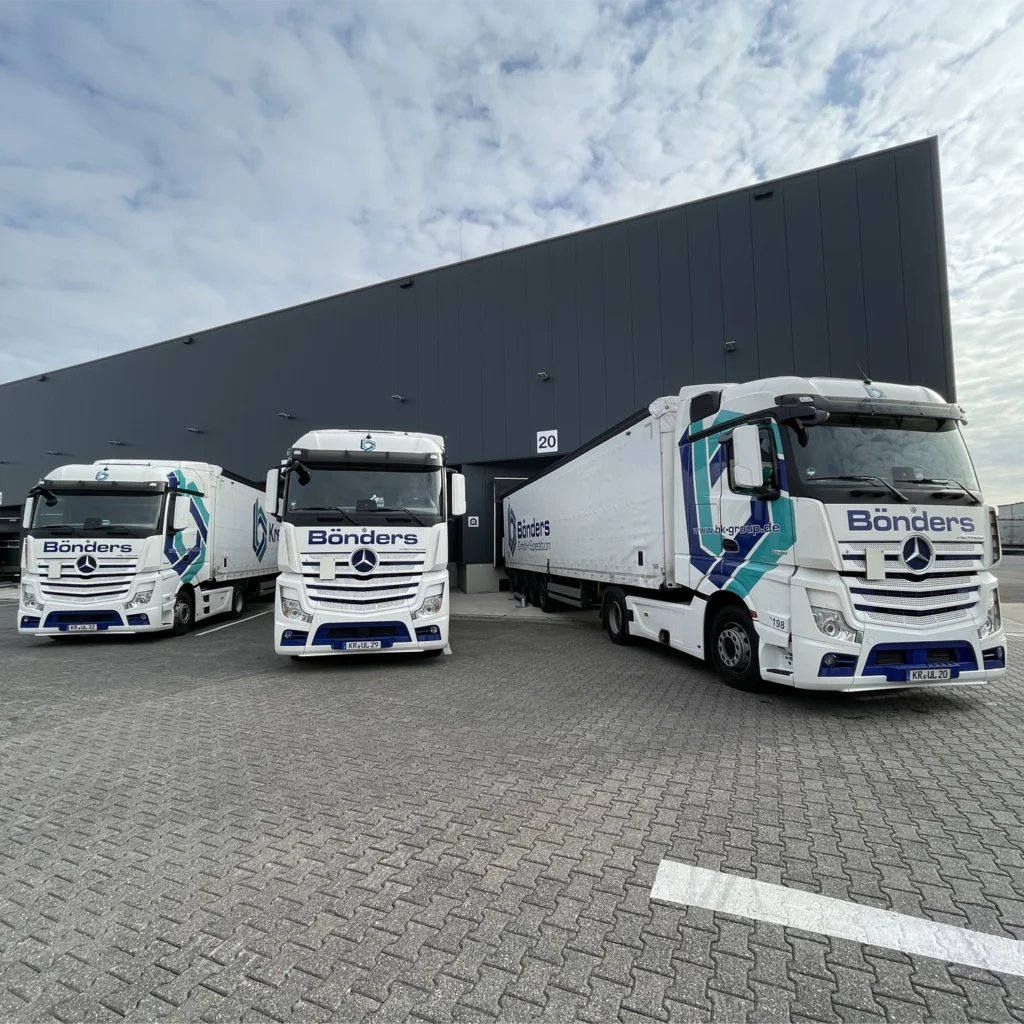 Three white trucks parked in front of the loading docks