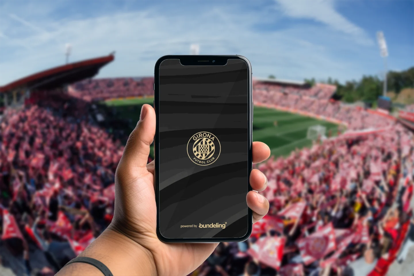 A hand holding the Girona FC Bundeling app