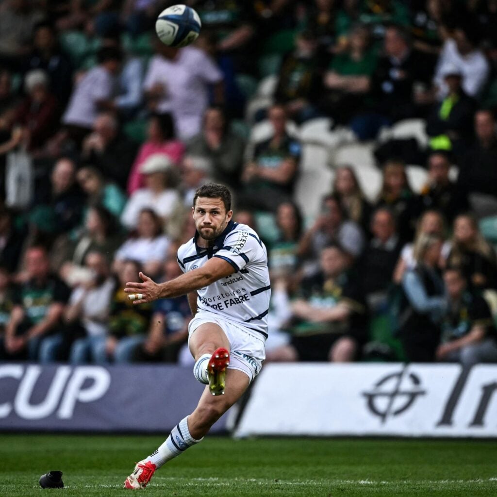 A rugby player taking a powerful kick against the ball