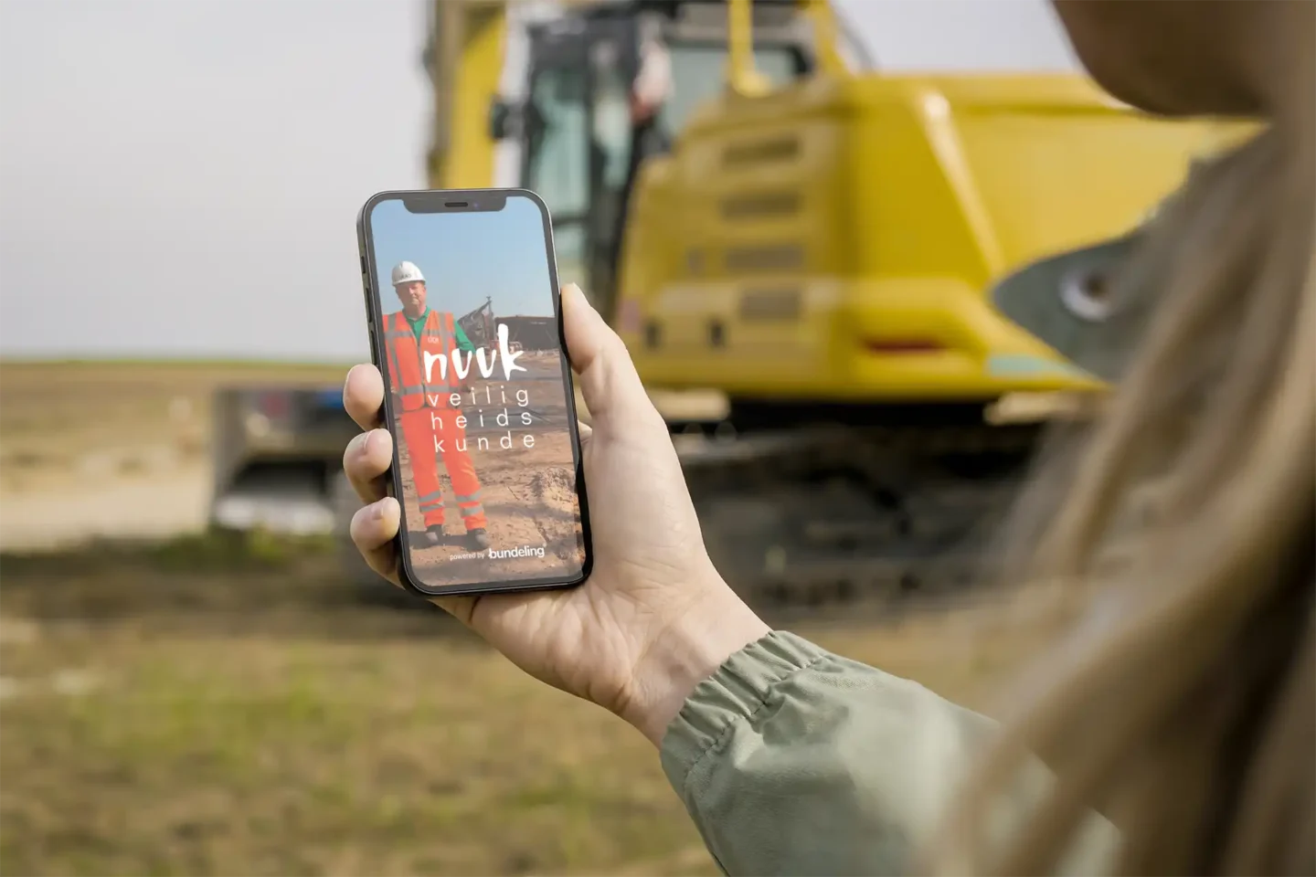 Smartphone op een bouwterrein met de NVVK app