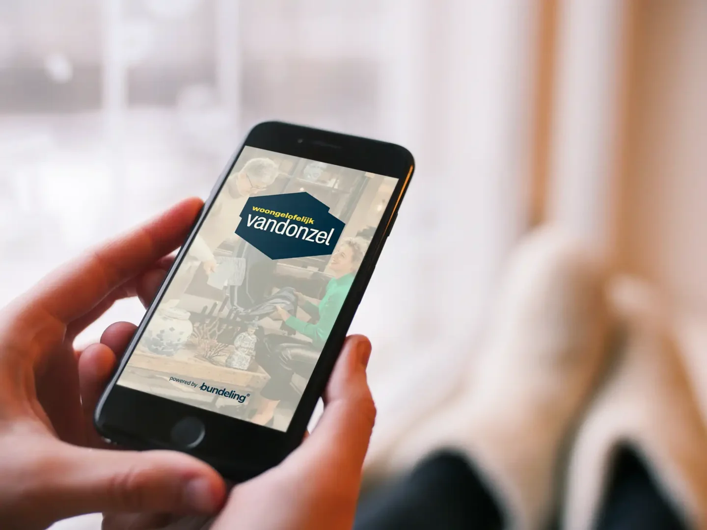 Handen die smartphone vasthouden met de woongelofelijk van Donzel app