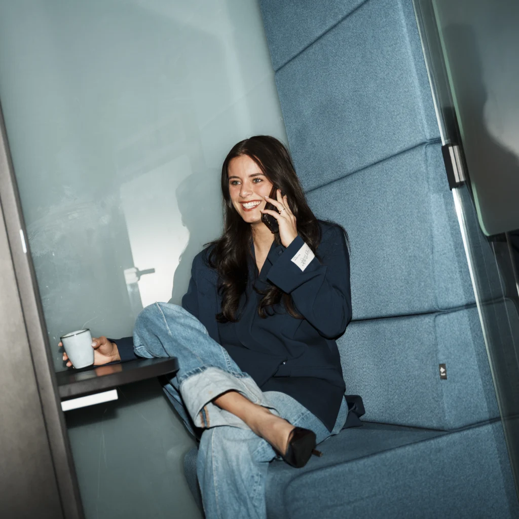 Young woman sitting in a with a coffee while calling.