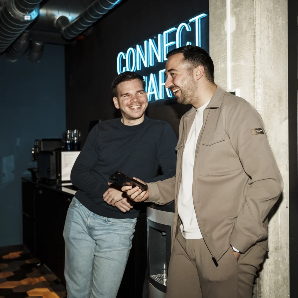 2 guys laughing while showing smartphone to eachother.