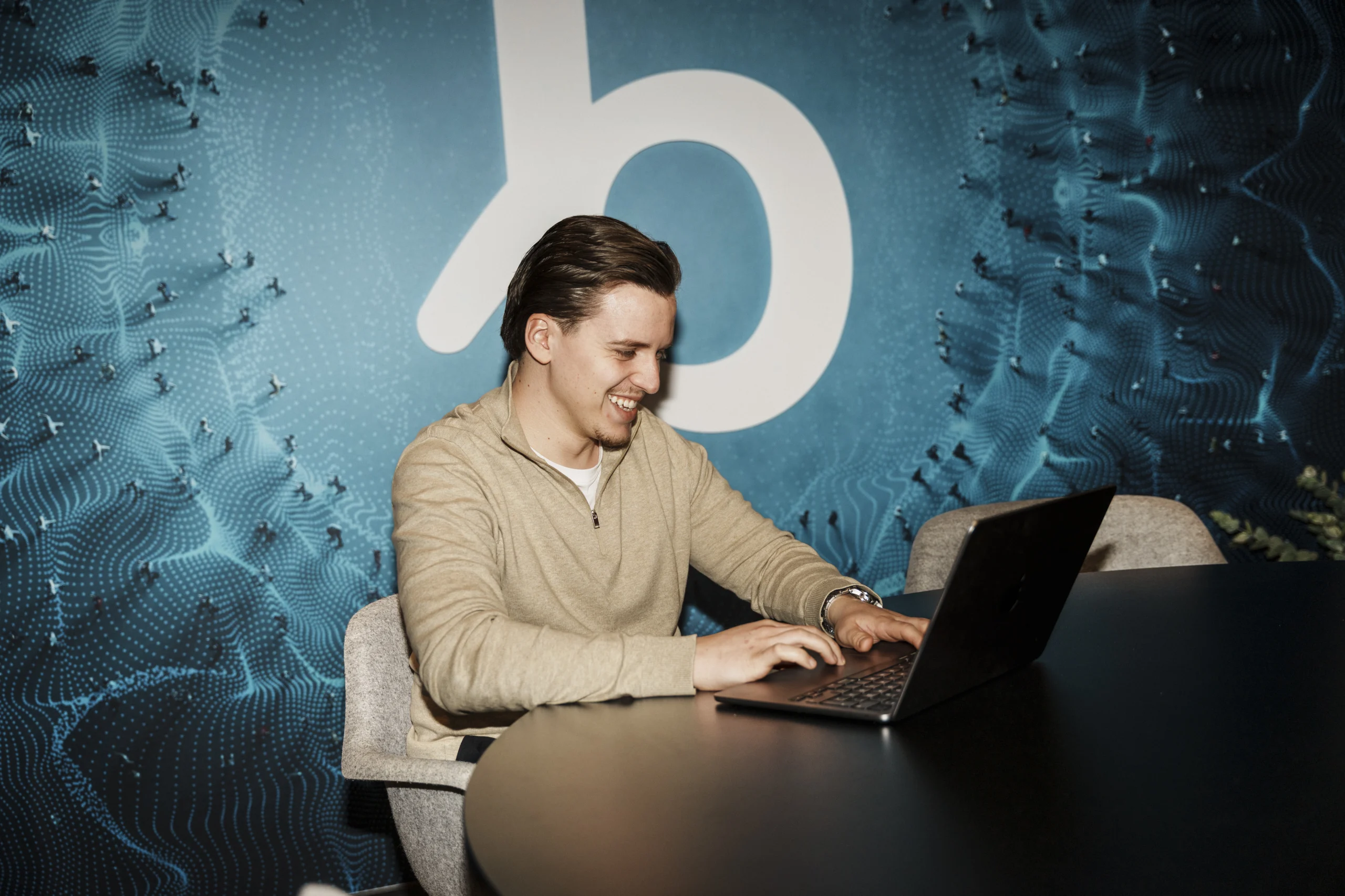 Smiling man working on laptop sitting in front of the Bundeling logo.