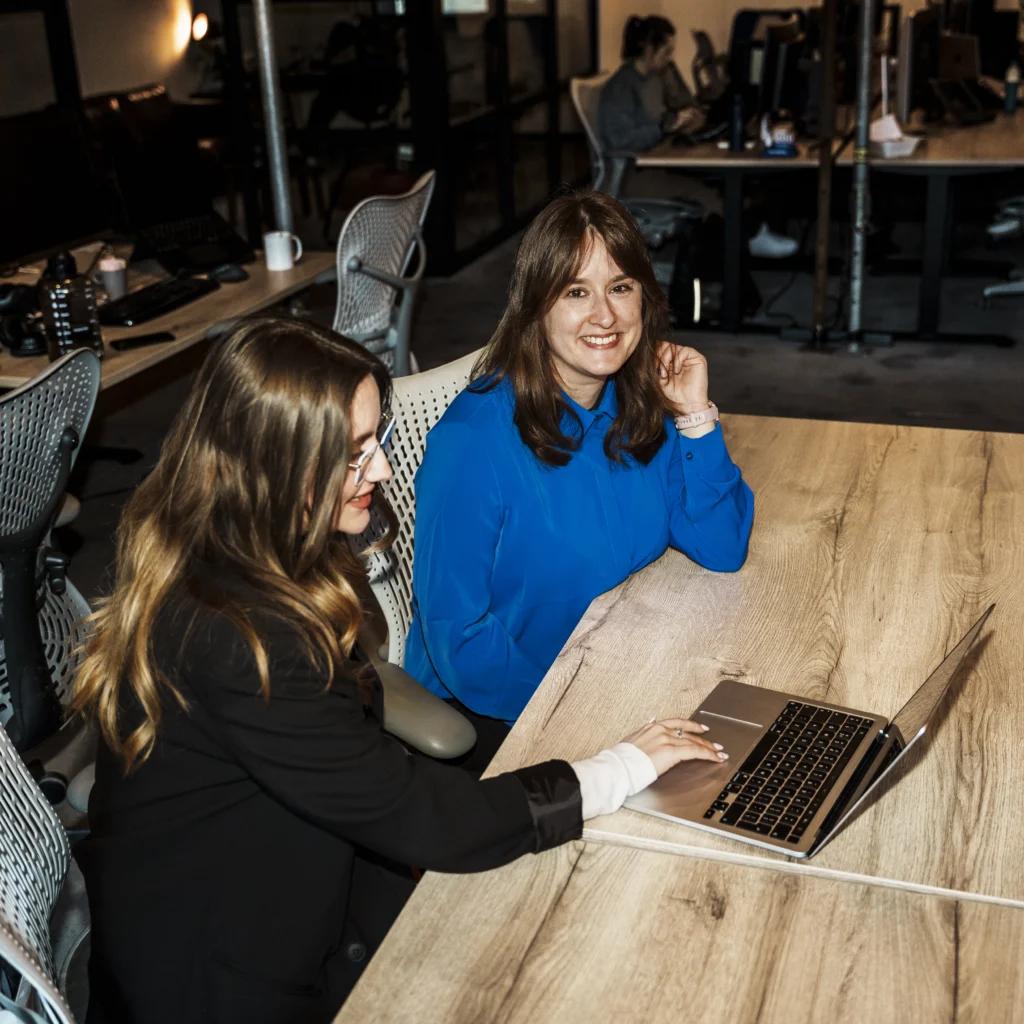 2 woman working while one of them smiles.