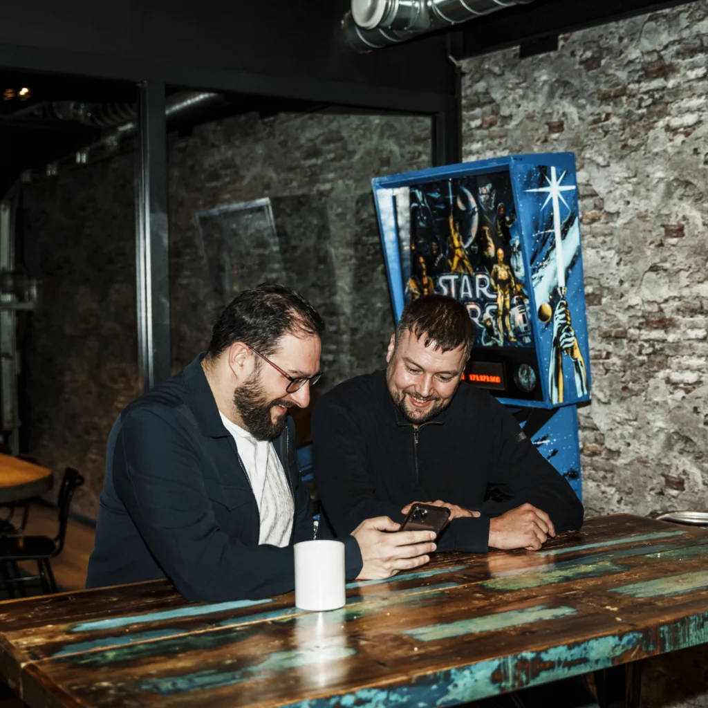 Two mature men in a industrial office looking at a smartphone.