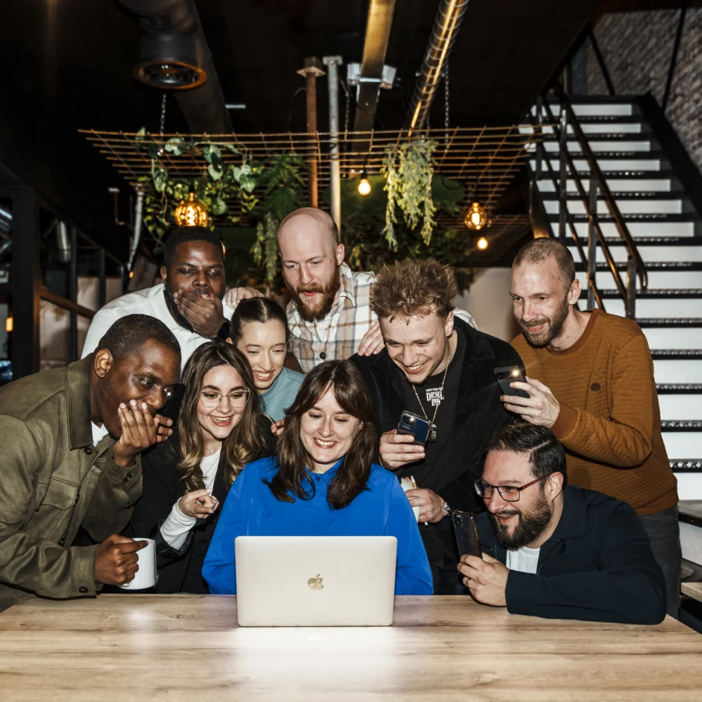 Large group amazed by what's shown on a laptop.