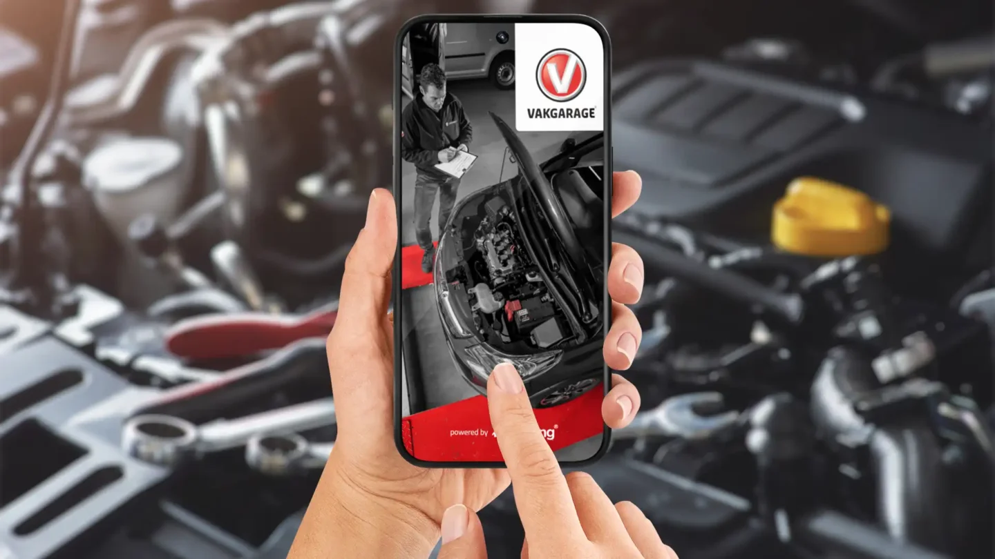Smartphone met de Vakgarage app boven een motorruimte van een auto